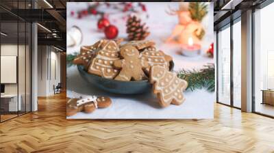 Various of Christmas cookies decorated with icing frosted in a bowl with holidays decoration atmosphere and candle light with green xmas tree branches  Wall mural