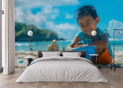 Joyful Asian Child Builds Sandcastle on Sunny Beach with Blue Bucket,Capturing Essence of Summer Fun Wall mural