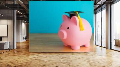 Pink piggy bank and mortarboard on wooden table with blue background copy space. Money savings and financial planning for education in university, college or international abroad study concept. Wall mural