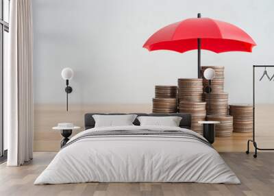 Stacked coins is protected by red umbrella on wooden table white wall background copy space. Assets wealth, money saving or money investment protection, security by insurance concept. Risk management. Wall mural