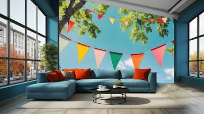 Summertime Festivities: Vibrant bunting flutters between leafy trees, a splash of color against a bright blue sky, evoking a joyous atmosphere of celebration and outdoor fun.  Wall mural