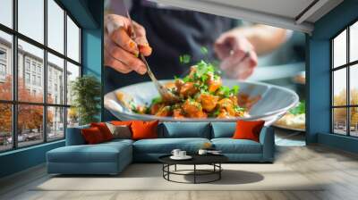 A chef garnishing a bowl of chicken tikka masala with fresh cilantro leaves, adding a burst of color and flavor to the classic Indian dish. Wall mural