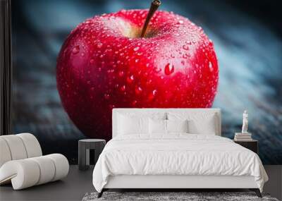 A close-up of a delicious red apple with droplets of water on its surface, resting on a wooden table, emphasizing the freshness and allure of the color red. Wall mural