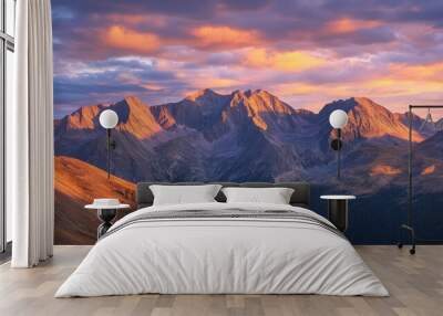 A dramatic sunrise over high mountain ranges, with the first light casting long shadows and illuminating the rugged peaks and valleys in warm hues. Wall mural