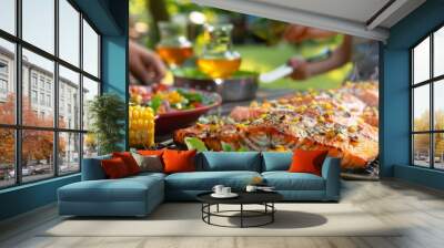 A family enjoying a seafood dinner with grilled salmon fillets, corn on the cob, and fresh salad on a picnic table. Wall mural