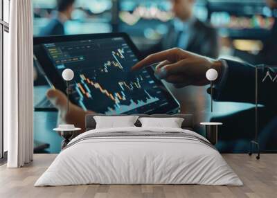 A financial analyst pointing to a candlestick chart on a tablet during a meeting. Wall mural