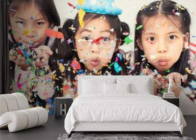 Group of Happy Asian Kids Blowing Colorful Confetti with Friends in Celebrate Event Cute Children Having Fun at School in Christmas New Year Party or Birthday Wall mural