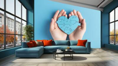 World autism awareness day concept. Child hands holding puzzle heart on light blue background Wall mural