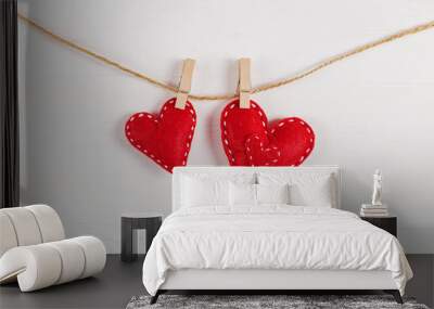 The concept of the preparation for Valentine's Day. Red hearts are held by clothespins on a jute rope, on a white wooden background. Copy space. Wall mural