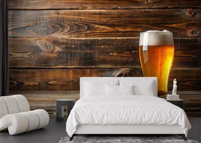 A single glass of golden beer with a thick head of foam rests upon a rustic wooden table, showcasing the allure of a simple yet satisfying beverage. Wall mural