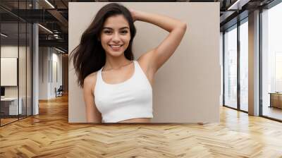 Young latin woman with bright skin wearing a white tank top showing her armpit on a beige background with copy space. Wall mural