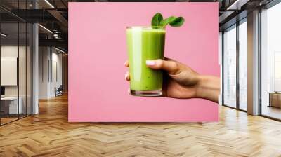 Green smoothie in a glass hand on a pink background Wall mural