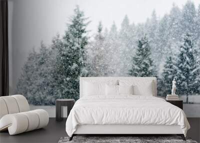 Snow falling heavily in an evergreen forest with focus on snowflakes creating a winter wonderland Wall mural