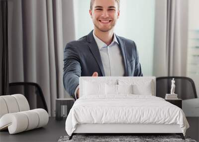 Smiling businessman extending hand for handshake in the office background Wall mural