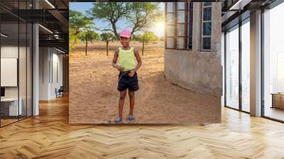 african girl with a big smile , in the village, playing with a wire car in the sand Wall mural