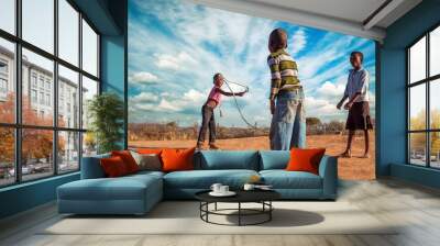 three african friends skipping rope in the village Wall mural