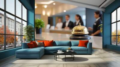 A golden service bell on a hotel reception desk, with blurred hotel staff in the background Wall mural