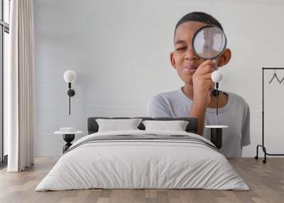 Boy holding the magnifying glass, Little kid boy holding and looking through magnifying glass showing a big eye Wall mural