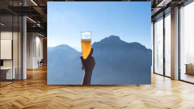 Hands lifting draft beer glass and happy enjoying harvest time at outdoor on beautiful mountain scene background.Celebration drinking beer.        Wall mural