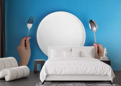 Female hands with cutlery and empty plate on coloured background. Meal preparation concept. Top view Wall mural