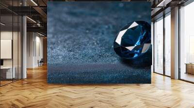 Azure Treasure: A dazzling blue gemstone sparkles on a dark, textured background, its facets catching the light in a mesmerizing display of brilliance and luxury.  Wall mural