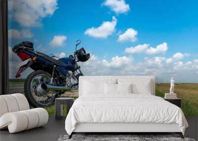 A motorcycle trip through the countryside in the summer. A blue motorcycle on a background of blue sky and white clouds. Wall mural