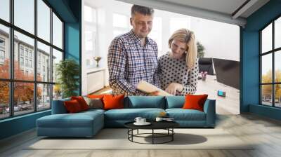 Two confident peoples reading notes together while working at a table in a modern office. Startup Wall mural