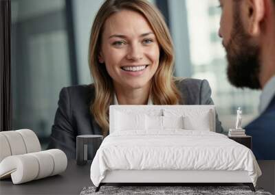 A happy corporate interview between a European male manager and a famale candidate. Young businesswoman smiling at colleague during a productive meeting in a modern office setting Wall mural