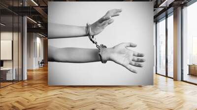 Arrested woman handcuffed hands. Prisoner or arrested terrorist, close-up of hands in handcuffs isolated on gray background. Criminal female hands locked in handcuffs. Black and white photography. Wall mural