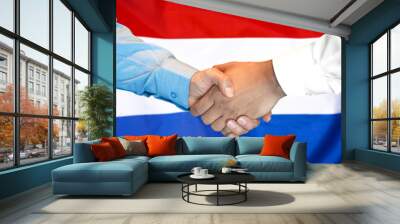 Business handshake on Netherlands flag background. Men shaking hands and Dutch flag on background. Support concept Wall mural