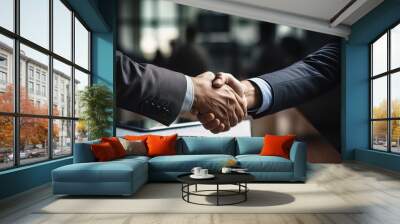 Close-up of two business people shaking hands, over a table with a document, negotiating in office Wall mural