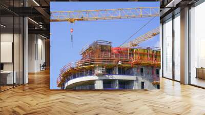 Construction site with cranes and a building against a blue sky.    Wall mural