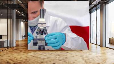 Female biochemist looking through a microscope against Poland flag background. Medical technology and pharmaceutical research and development of science concept in Poland Wall mural