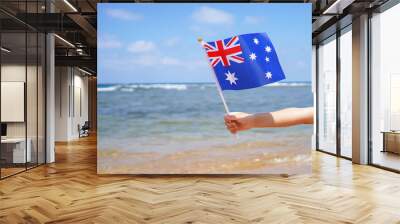 Hands of kid girl holding Australia flag against the sea horizon. 26th of January Independence day of Australia, concept. Wall mural