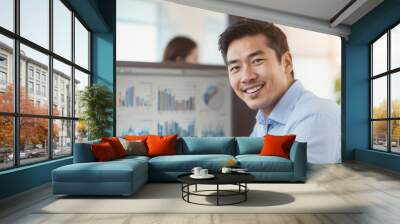 Portrait of happy businessman against white screen background with desktop computer charts in office Wall mural