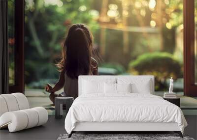 A little girl is meditating while sitting in the room at home indoor with garden view Wall mural