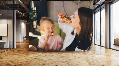 Mother and daughter eat pizza in a cafe. Wall mural