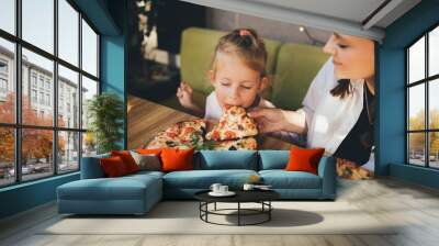 Mother and daughter eat pizza in a cafe. Wall mural