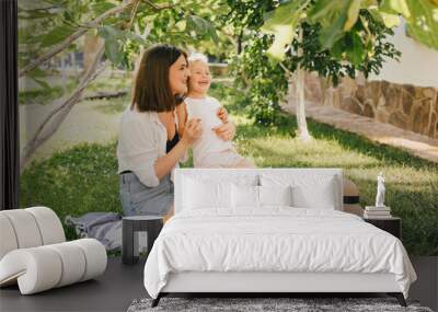 Young mother and her child having cozy summer picnic with fresh lemonade and fruits in a park. Wall mural