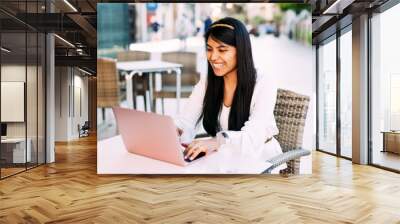 Latin young brunette woman sitting on bar terrace working with laptop Wall mural