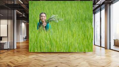 Pretty girl is happy in natural green organic Thai jasmine rice paddy crop on a plantation field growing during the growing season agriculture farming. Wall mural