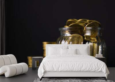 Coins stacks and gold coin money in the glass jar on dark background, for saving for the future banking finance concept. Wall mural