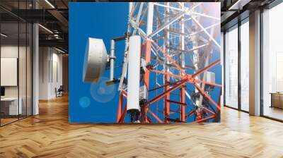 mobile phone communication antenna tower with satellite dish on blue sky background Wall mural