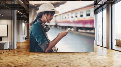 Asian tourist teenage girl at train station using smartphone map, social media check-in, or buy ticket booking. Modern travel app technology, lone traveler, Summer vacation railroad adventure concept Wall mural