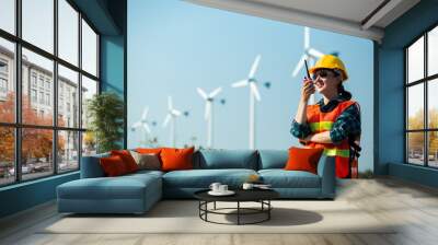 Young engineer woman holding a walkie talkie to check wind turbine system, concept of renewable energy Wall mural