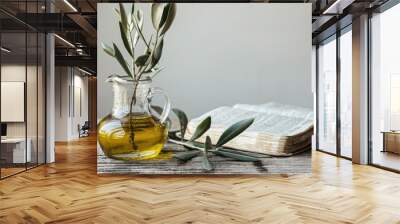 Anoint. Pure Olive Oil in Glass Jar, Open Bible Book, and Green Olive Branch on Wooden Table with White Background. Symbol of God's Holy Spirit Wall mural