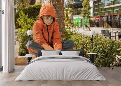 the boy is sitting on a bench in the park sad, a lonely child is sitting on a bench Wall mural