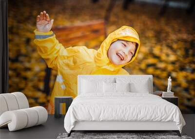 Child in the yellow raincoat walks in the forest and has fun Wall mural