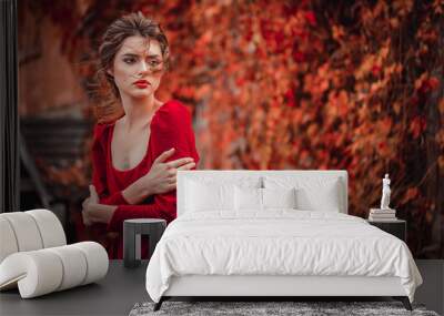 Portrait of Beautiful girl in a burgundy and red dress on a background of autumn grape leaves in the park, October Wall mural