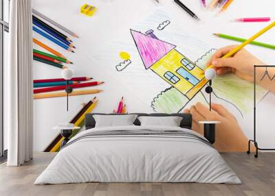 child girl draws house with multicolored felt-tip pens on a white sheet. Wall mural